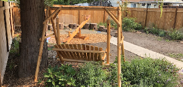 Wooden swing in a peaceful backyard garden with mulch and greenery
