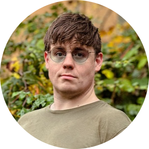 Portrait of a young man with glasses and short brown hair wearing a green shirt outdoors